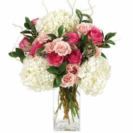 White hydrangeas with light and hot pink roses in a clear rectangular glass vase