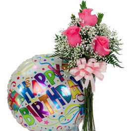 Pink roses in a glass vase beside a birthday balloon