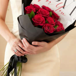 Woman holding a bouquet of red roses wrapped in black paper