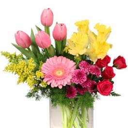 Mixed bouquet in a clear glass vase with pink tulips, yellow flowers, and red roses