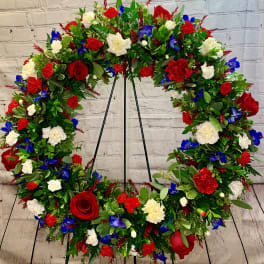 Large floral wreath with red, white, and blue flowers on a stand