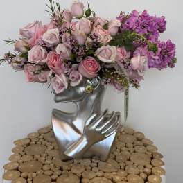 Pink and purple rose bouquet in a silver face-shaped vase