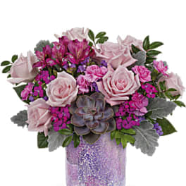 Pink roses and magenta flowers arranged in a purple glass vase