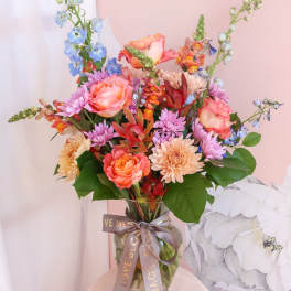 Colorful mixed bouquet in a glass vase with a ribbon