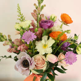 Mixed bouquet in a glass vase with orange, purple, and blush flowers