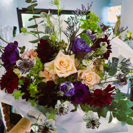Hand-tied bouquet of cream, purple, and burgundy flowers with eucalyptus