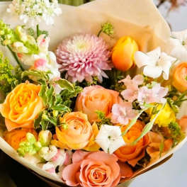 Bouquet of orange and pink roses with white flowers and a pink chrysanthemum