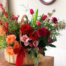 Basket arrangement of red and peach roses with tulips and berries