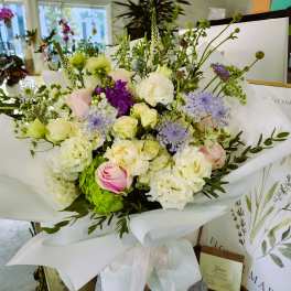 Bouquet of white, pink, and purple flowers wrapped in white paper