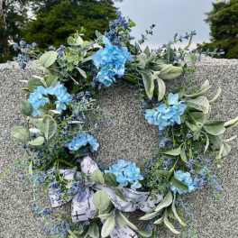 Blue floral wreath with ribbon on a gray stone surface
