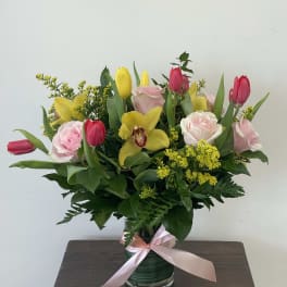Pink and yellow tulips with roses in a glass vase