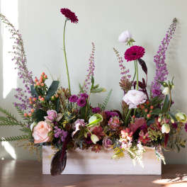 Mixed floral arrangement in a white rectangular box with pink and purple blooms