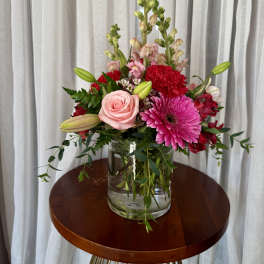 Mixed bouquet in a clear glass vase with pink and red blooms