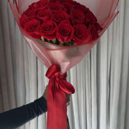 Bouquet of red roses wrapped in pink paper with a red ribbon