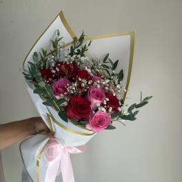 Bouquet of red and pink roses wrapped in white paper with a pink ribbon