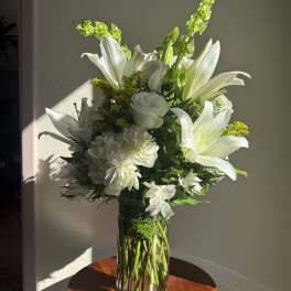 White lilies and roses arranged in a clear glass vase