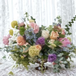 Mixed pastel flower arrangement in a low pedestal vase