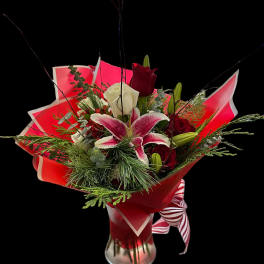 Bouquet of red and white roses with a pink lily in a glass vase