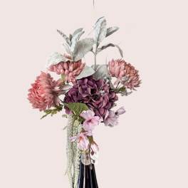 Pink and purple floral arrangement in a dark glass vase