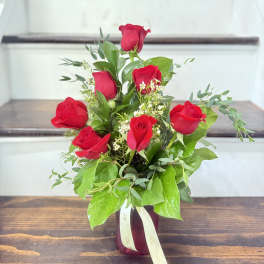 Bouquet of red roses in a burgundy vase with a ribbon