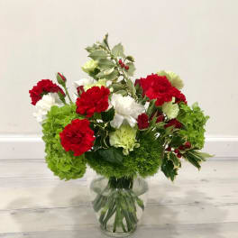 Red and white carnations in a glass vase with green hydrangeas