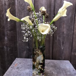 Tall calla lily arrangement in a decorated glass vase