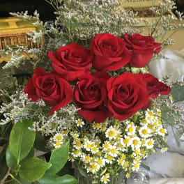 Red roses and small white daisies in a clear glass vase