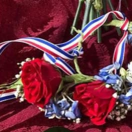 Red roses with blue flowers and tricolor ribbon on velvet fabric