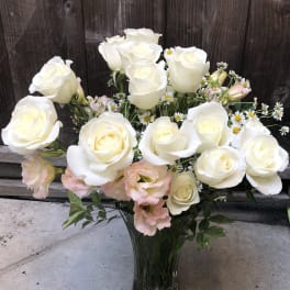 White roses and pale pink blooms in a clear glass vase