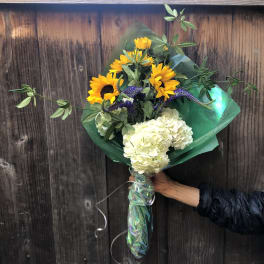 Bouquet of sunflowers and white hydrangeas wrapped in green paper