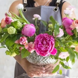 Pink and peach flowers arranged in a silver bowl vase