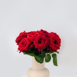 Red roses arranged in a beige vase