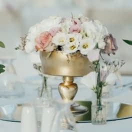 Pastel floral centerpiece in a gold vase on a table