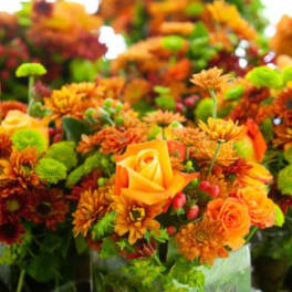Orange and green floral arrangement in a clear glass vase