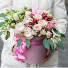 Pink and white roses in a round pink box with a satin ribbon