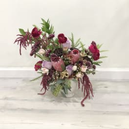 Mixed pink and burgundy floral arrangement in a white vase