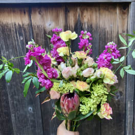 Handheld bouquet with pink and yellow flowers and a large protea
