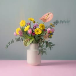 Mixed bouquet of yellow and pink flowers in a white vase