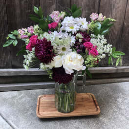 Mixed bouquet in a clear glass vase with white, pink, and burgundy flowers