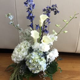White hydrangeas with blue delphinium and white calla lilies in a low arrangement
