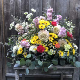Mixed bouquet of yellow, pink, white, and red flowers on a wooden table