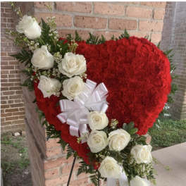 Heart-shaped red floral arrangement with white roses and a white bow