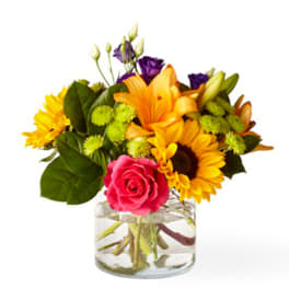 Mixed bouquet of bright flowers in a clear glass vase