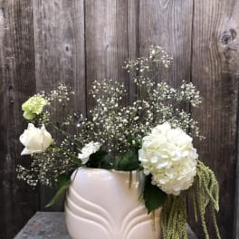 White floral arrangement in a pale pink vase