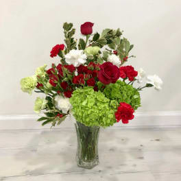 Mixed red, white, and green flowers arranged in a clear glass vase