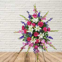 Standing floral spray with pink roses, white lilies, and purple accents