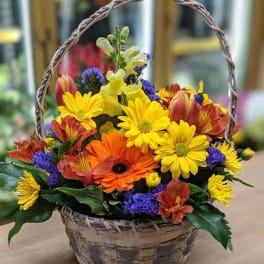Basket of mixed yellow, orange, red, and purple flowers