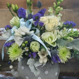 Mixed bouquet in a gray polka-dot elephant vase with blue ribbon
