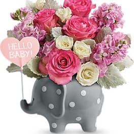 Pink and white flower arrangement in a gray elephant planter with a Hello Baby sign