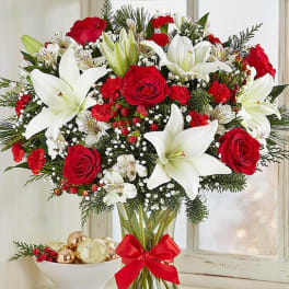 Bouquet of red roses and white lilies in a glass vase with a red ribbon